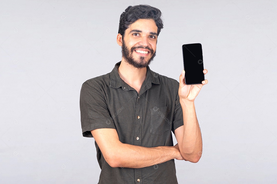 Homem jovem barbudo segurando celular smartphone sobre fundo isolado branco