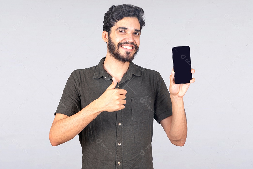 Homem jovem barbudo segurando celular smartphone sobre fundo isolado branco