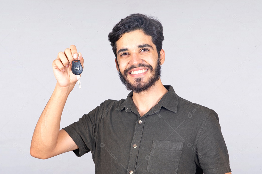 Homem jovem barbudo segurando chave de carro sobre fundo isolado branco