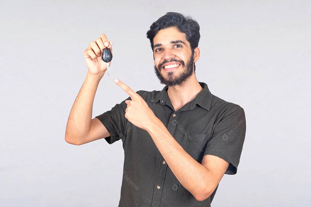 Homem jovem barbudo segurando chave de carro sobre fundo isolado branco