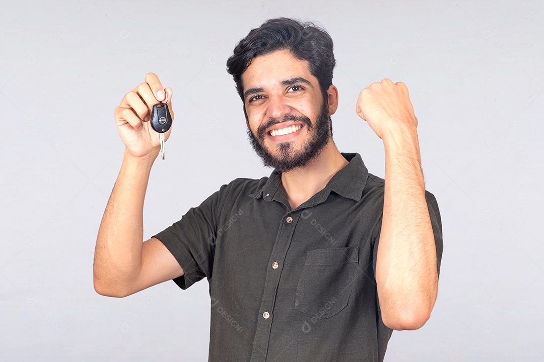 Homem jovem barbudo segurando chave de carro sobre fundo isolado branco