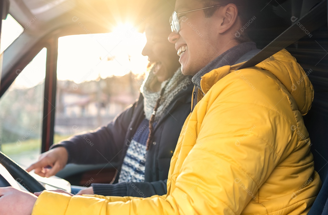 Casal hipster viajando juntos em transporte de van adaptado - ele dirigindo e ela procurando o mapa ao pôr do sol - conceito de inspiração de estilo de vida indie - foco seletivo