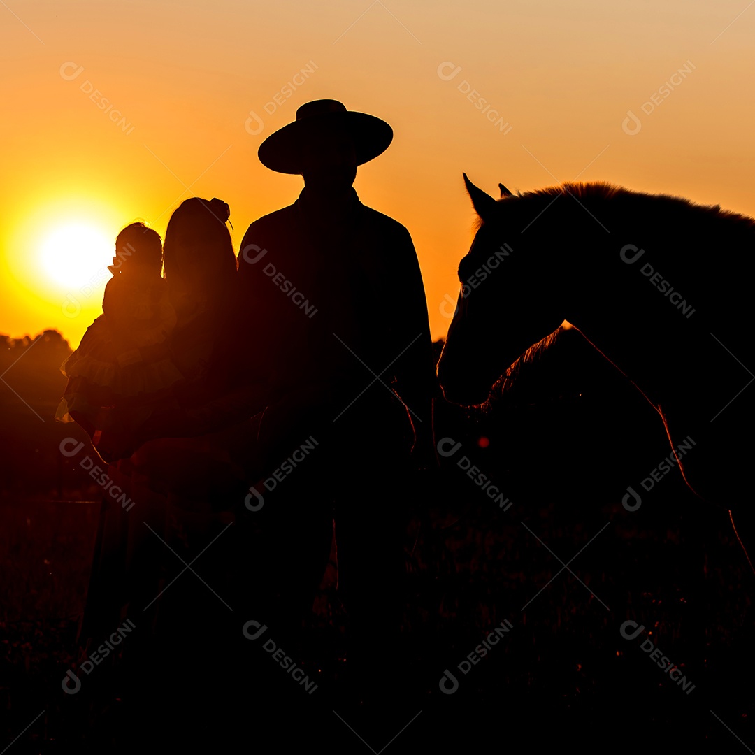 Silhueta da família gaúcha com cavalo ao pôr do sol
