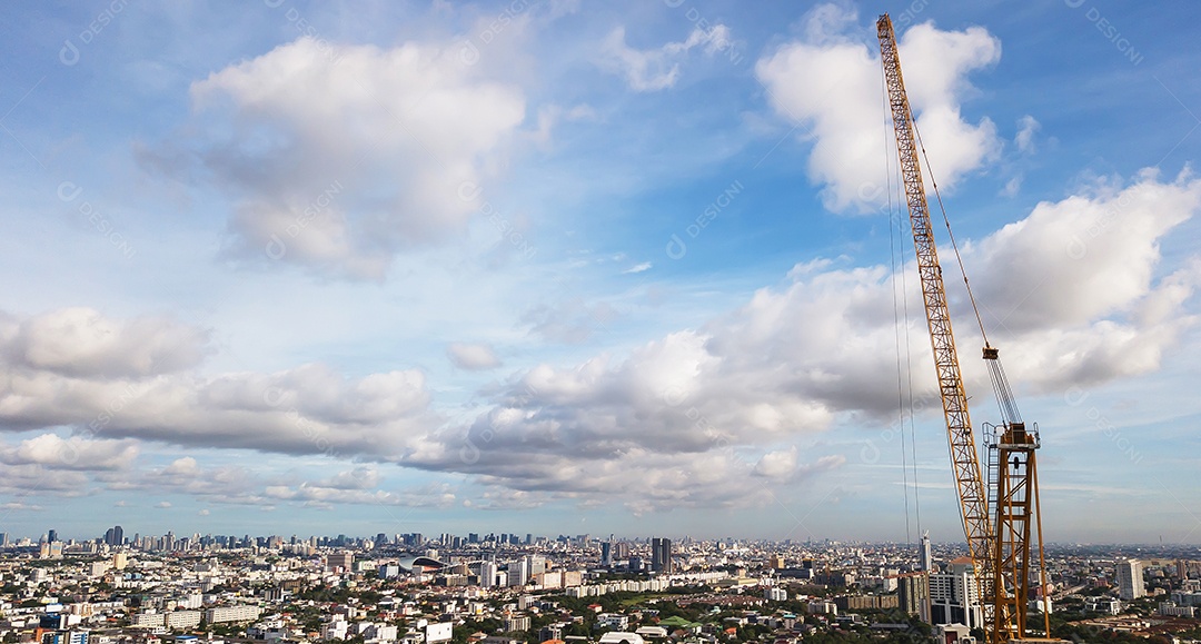 Grande canteiro de obras, incluindo vários guindastes trabalhando em um complexo de construção, com céu azul claro e sol