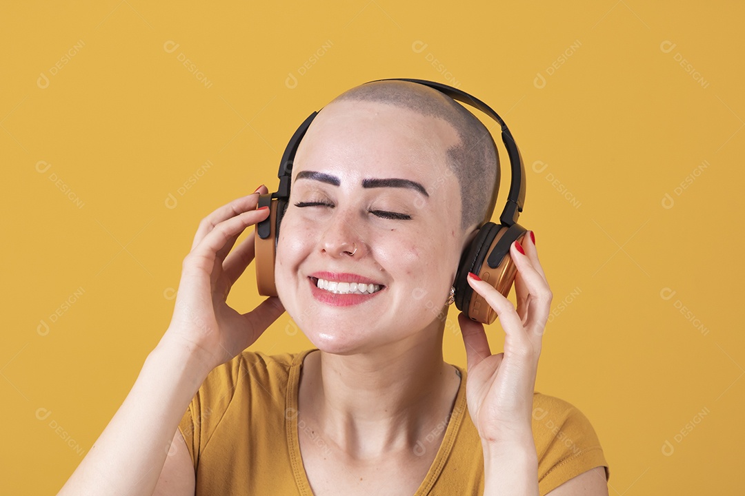 Mulher jovem careca usando blusa bege com fone de ouvido em conceito de câncer, outubro rosa