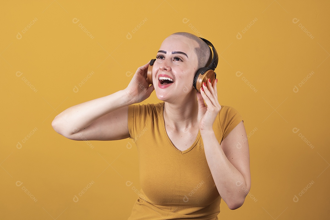 Mulher jovem careca usando blusa bege com fone de ouvido em conceito de câncer, outubro rosa