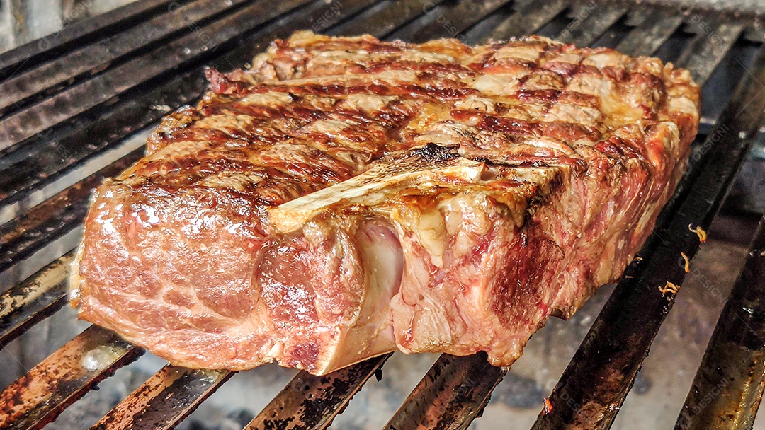 Bife de short costela sendo grelhado, vista lateral.