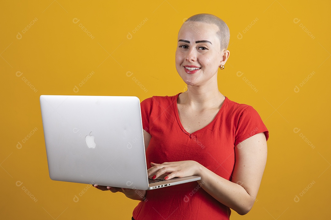 Mulher jovem careca usando blusa vermelha segurando um notebook