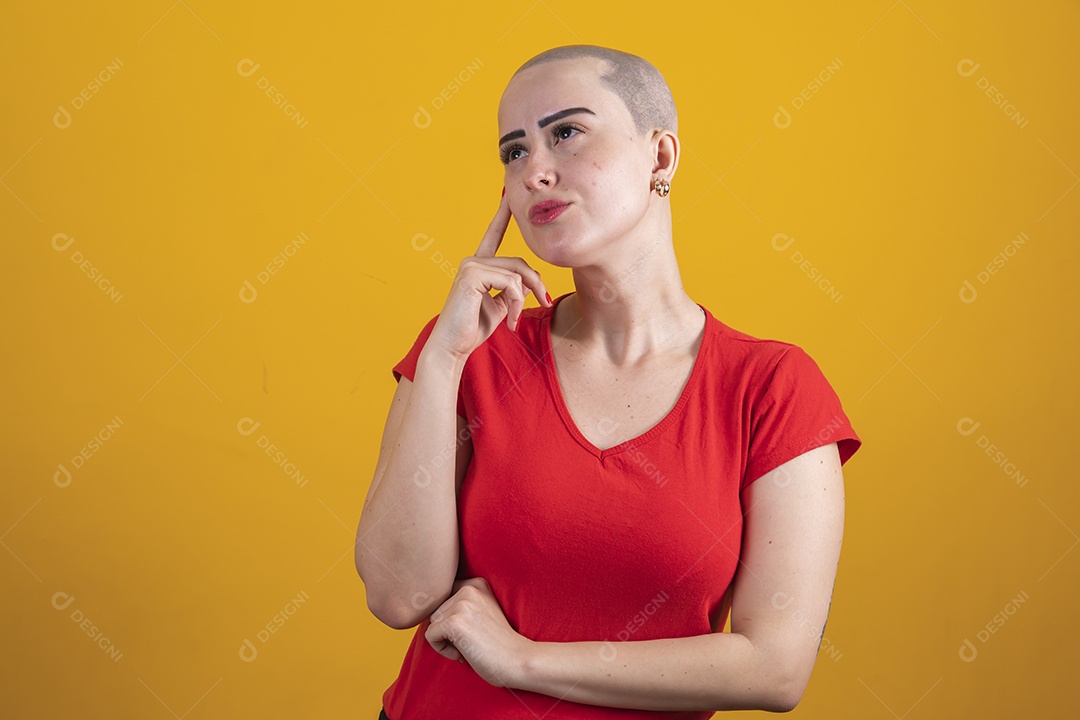 Mulher jovem careca usando blusa vermelha em conceito de câncer, outubro rosa