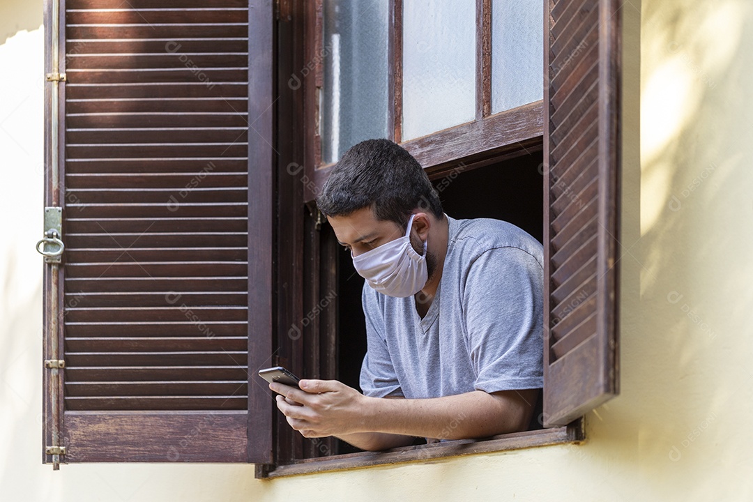 Homem jovem usando mascara mexendo em seu celular