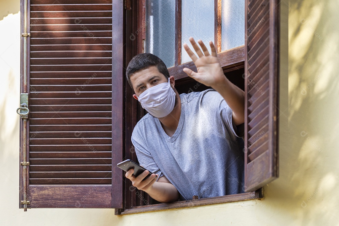 Homem jovem usando mascara mexendo em seu celular