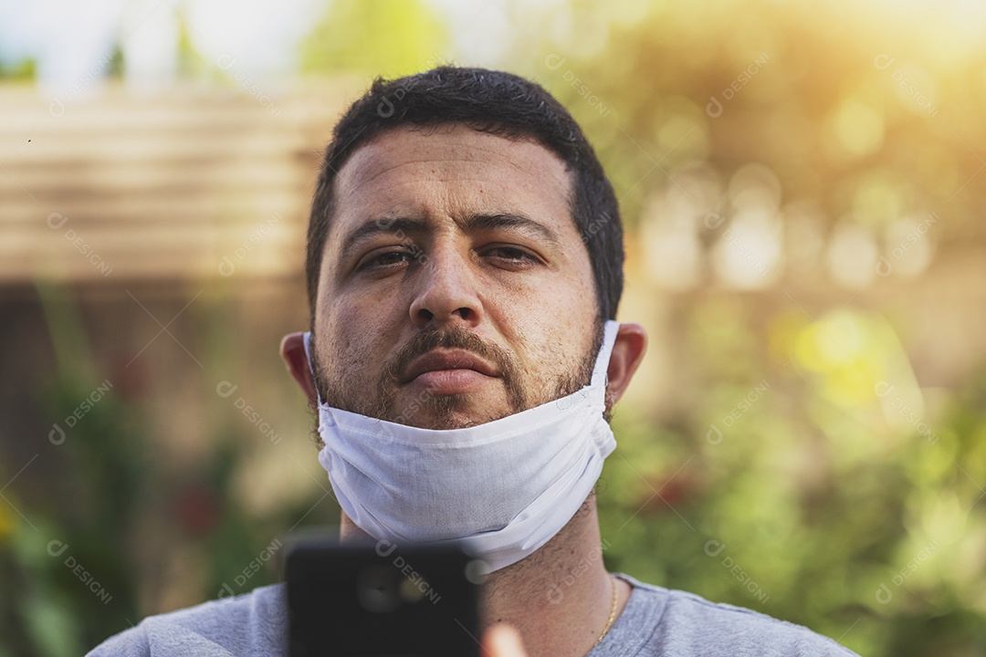 Homem jovem usando mascara mexendo celular