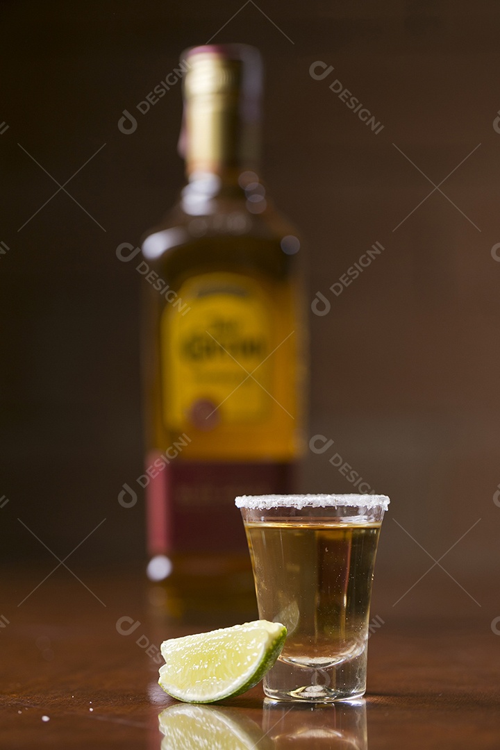 Dose de bebida alcoólica e fatia de limão sobre mesa de madeira