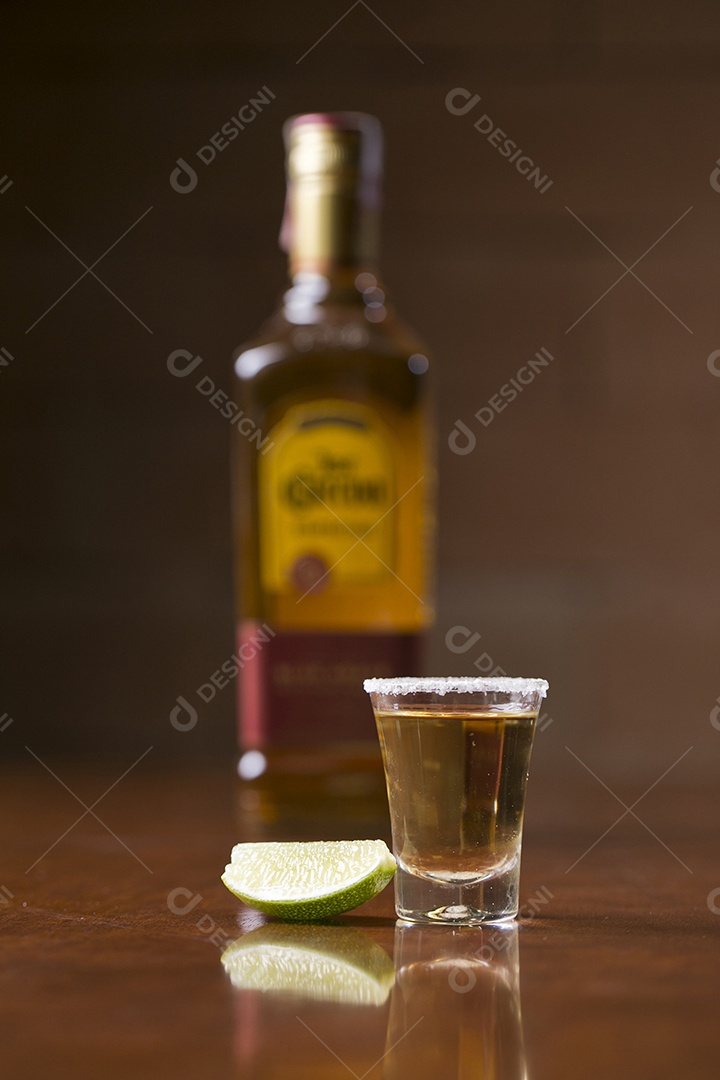 Dose de bebida alcoólica e fatia de limão sobre mesa de madeira