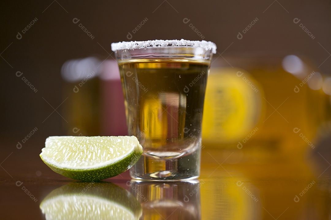 Dose de bebida alcoólica e fatia de limão sobre mesa de madeira