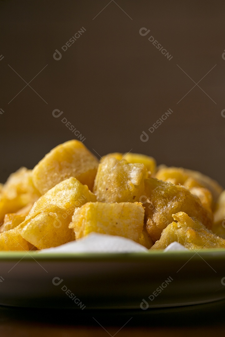 Porção de mandioca frita sobre a mesa de madeira