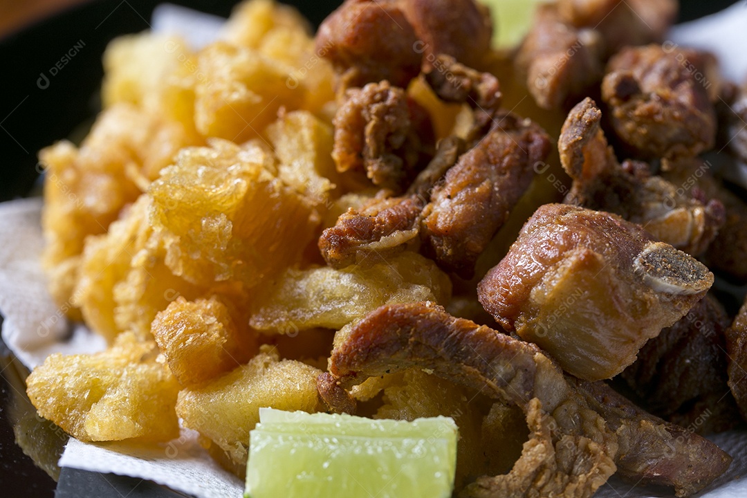 Porção de mandioca frita com costelinha de porco sobre a mesa