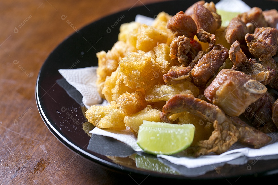 Porção de mandioca frita com costelinha de porco sobre a mesa