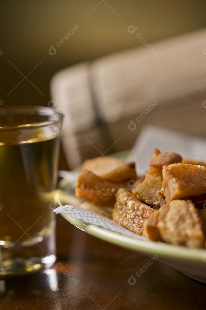 Porção de torresmo frito e cerveja sobre a mesa