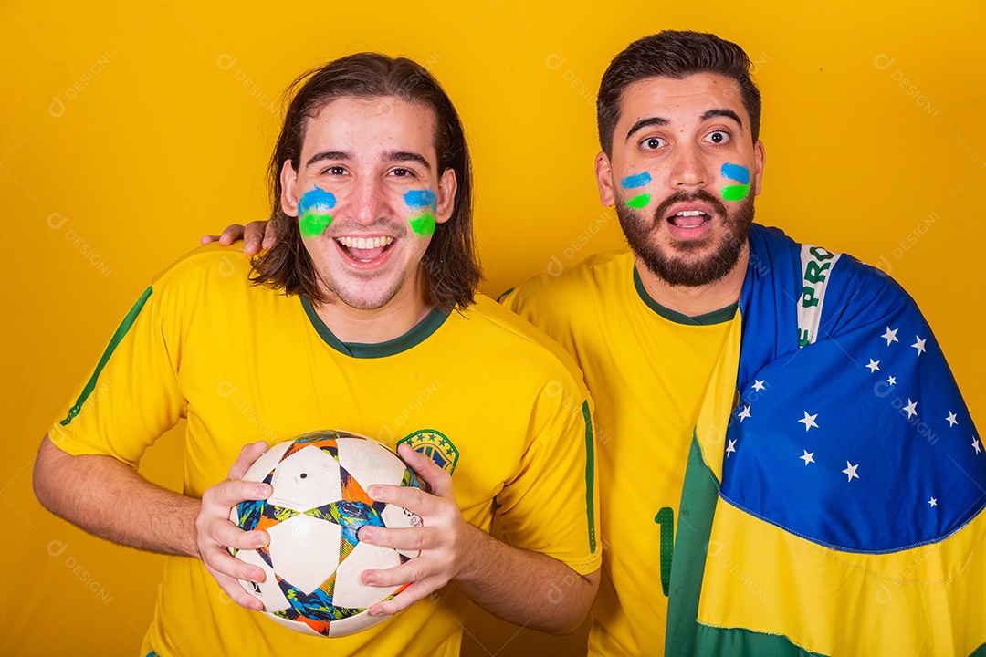 Dois homens jovens torcedores brasileiros sobre fundo isolado amarelo