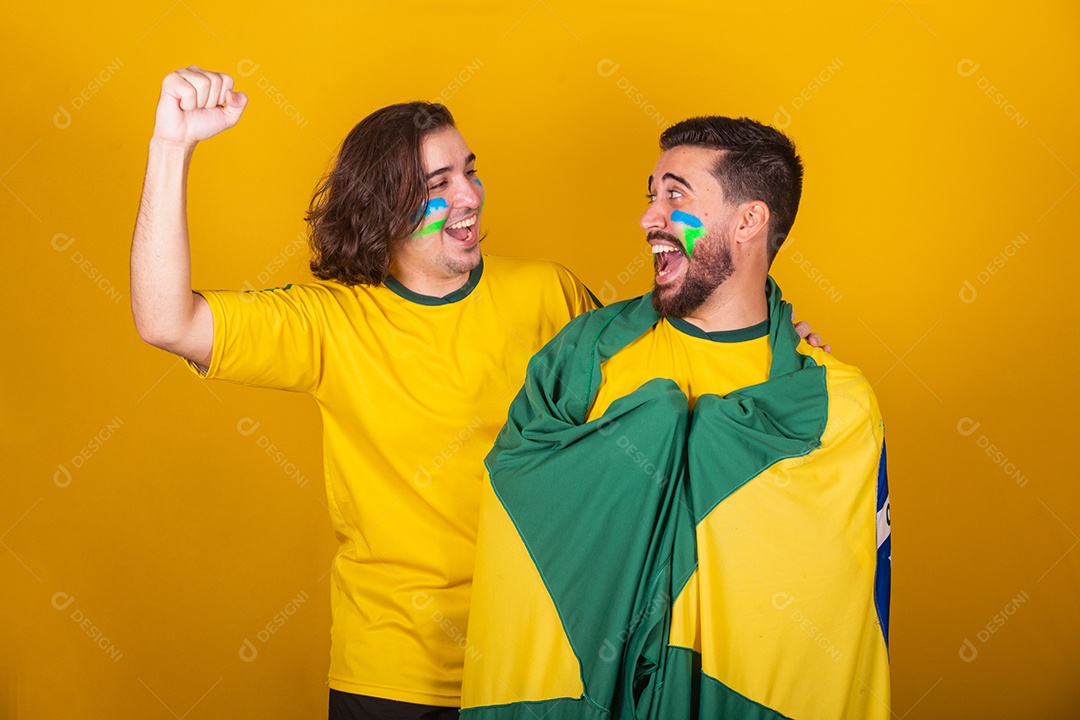 Dois homens jovens torcedores brasileiros sobre fundo isolado amarelo