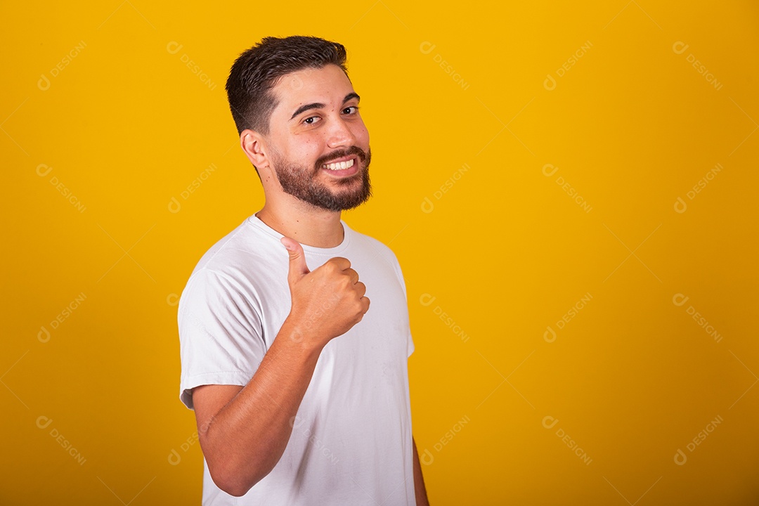 Homem jovem brasileiro sorridente barbudo fundo amarelo