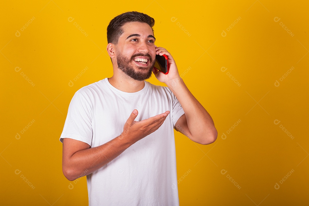 Homem jovem brasileiro segurando celular smartphone fundo amarelo