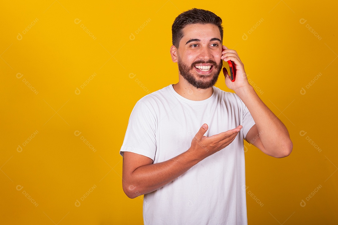 Homem jovem brasileiro segurando celular smartphone fundo amarelo
