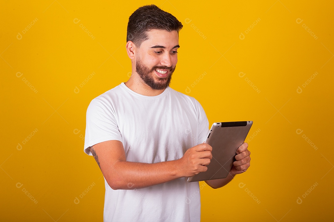 Homem jovem brasileiro segurando celular smartphone fundo amarelo