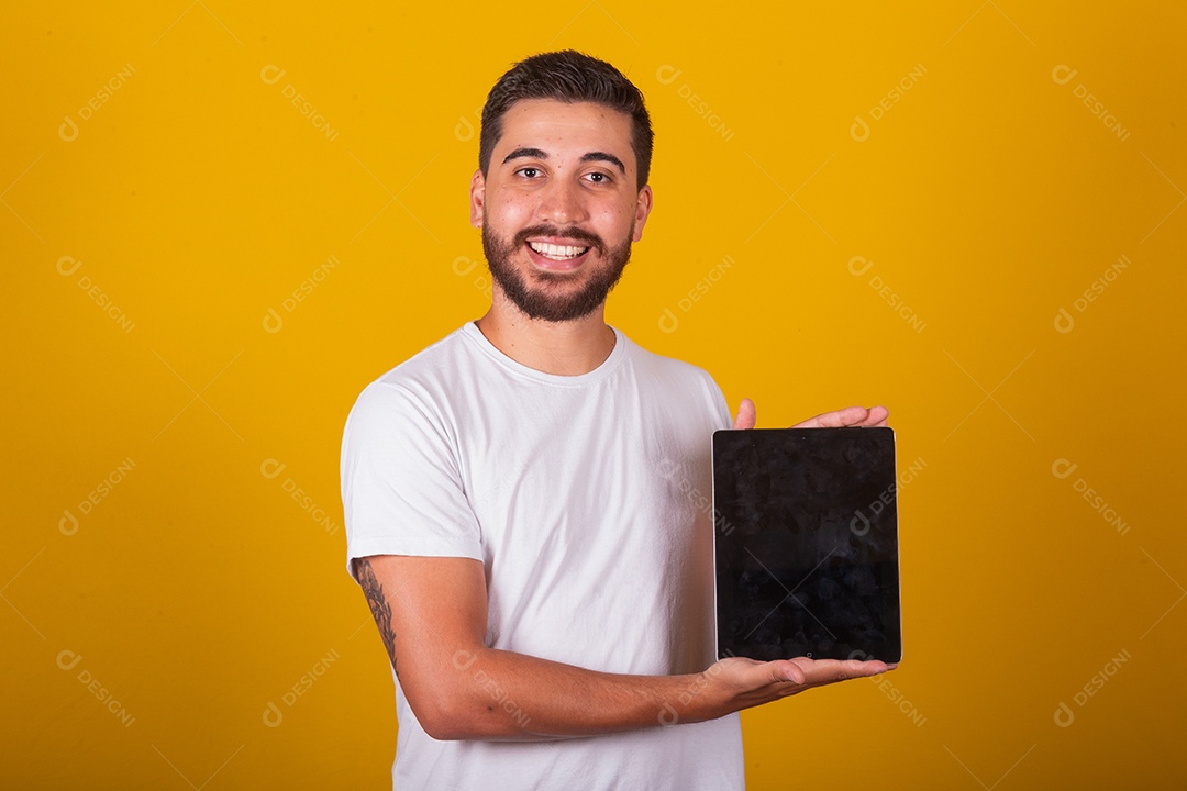 Homem jovem brasileiro segurando celular smartphone fundo amarelo