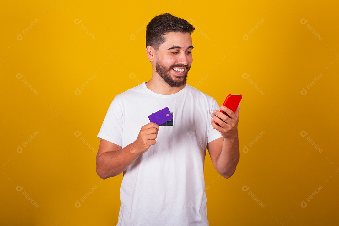 Homem jovem segurando segurando celular e fazendo compras no cartão