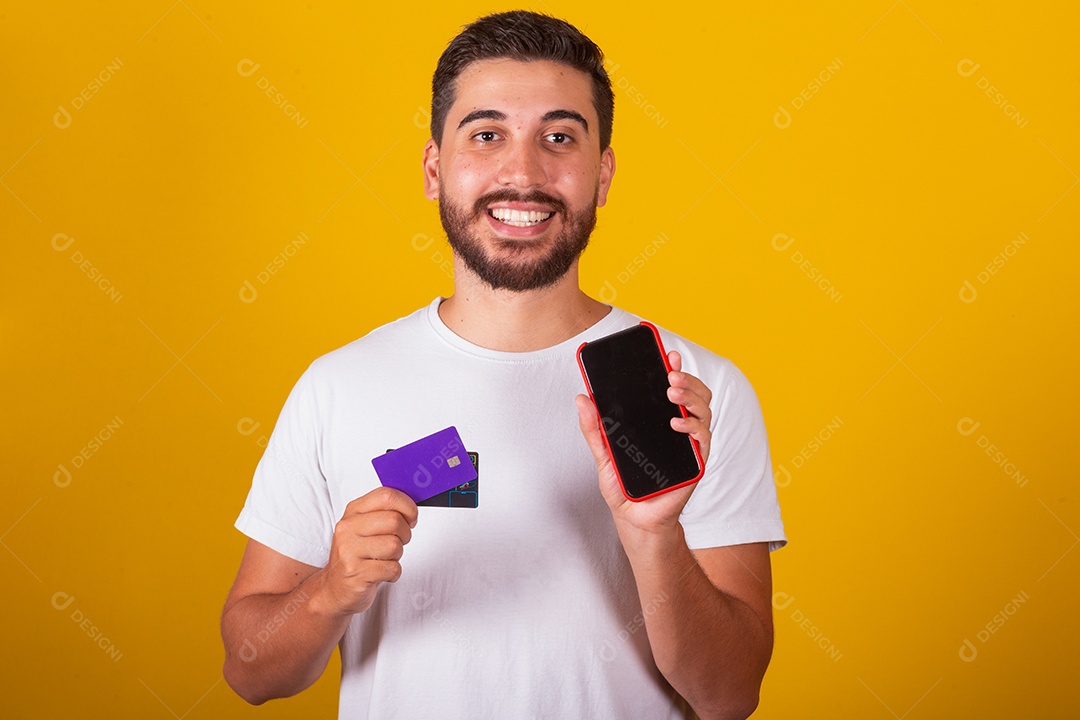 Homem jovem segurando segurando celular e fazendo compras no cartão