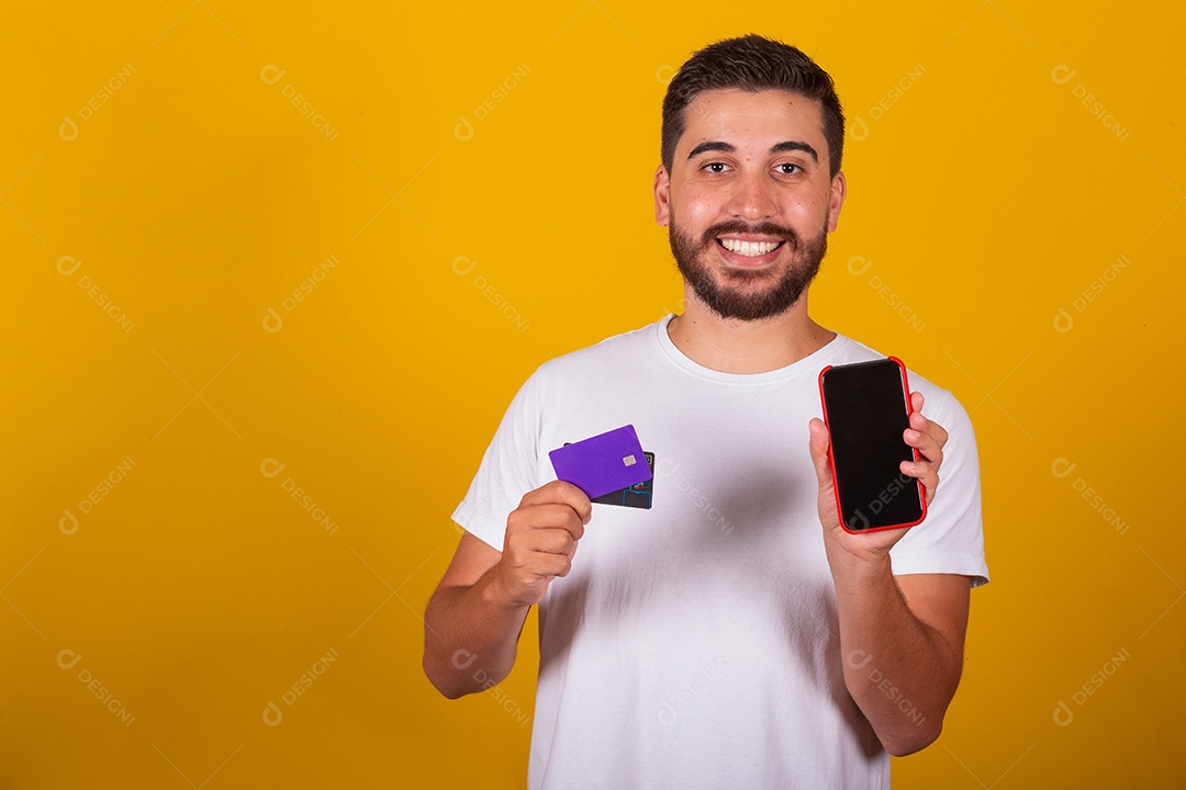 Homem jovem segurando segurando celular e fazendo compras no cartão