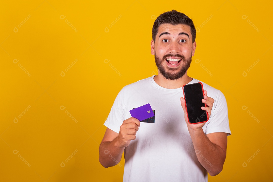 Homem jovem segurando segurando celular e fazendo compras no cartão