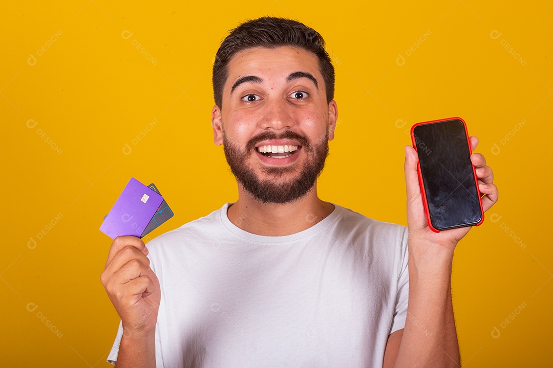 Homem jovem segurando segurando celular e fazendo compras no cartão