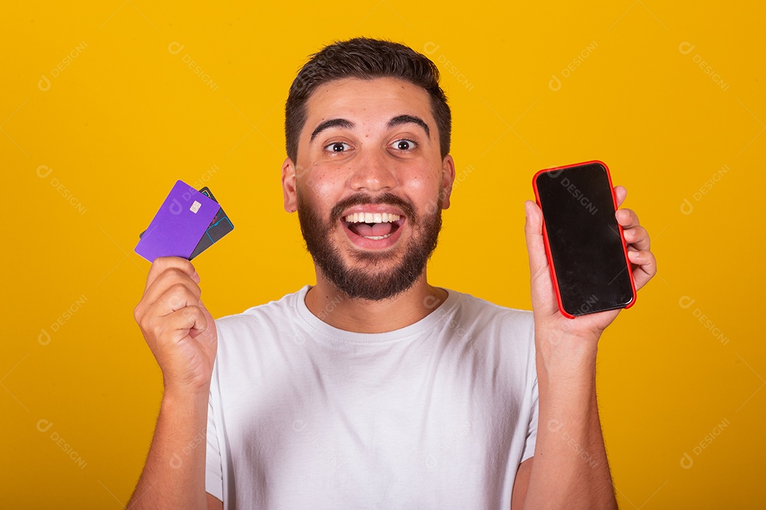 Homem jovem segurando segurando celular e fazendo compras no cartão