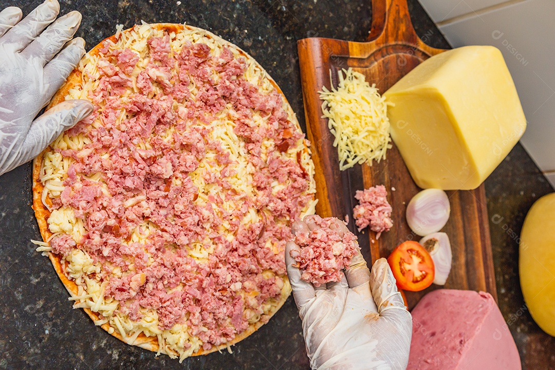 Pizza mista de presunto e queijo muçarela sendo preparada, pré-assada,