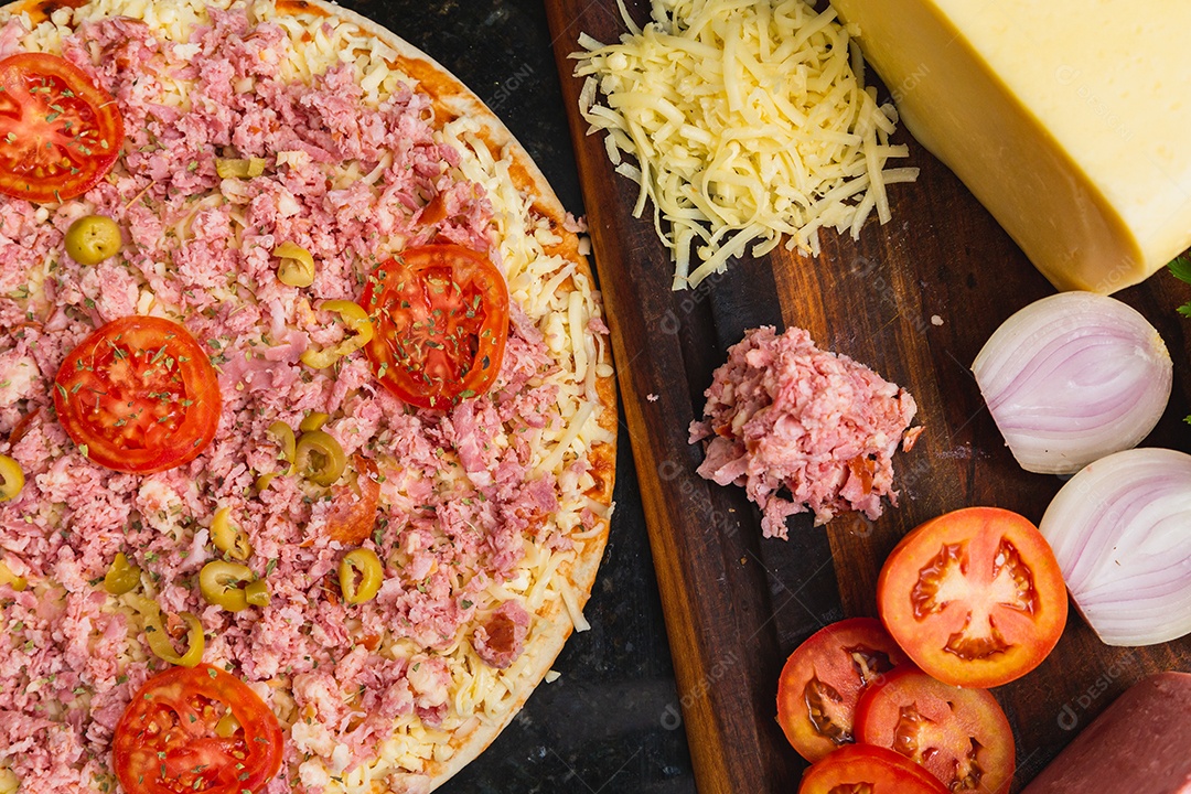 Pizza mista de presunto e queijo muçarela sendo preparada, pré-assada