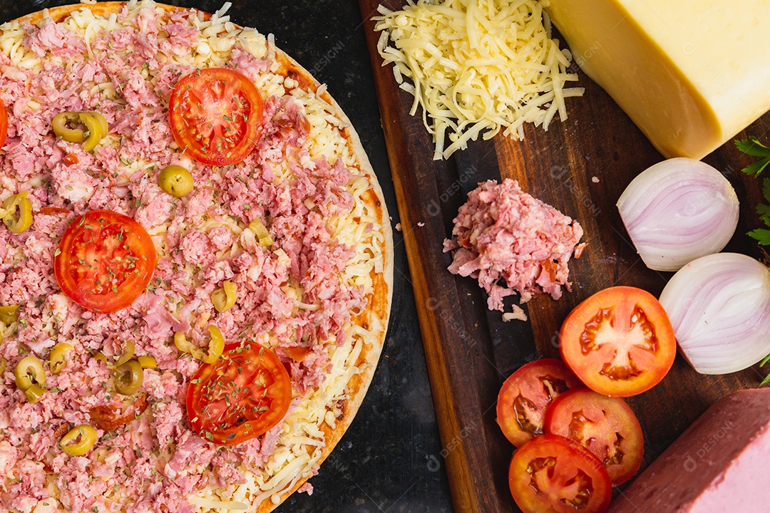 Pizza mista de presunto e queijo muçarela sendo preparada, pré-assada