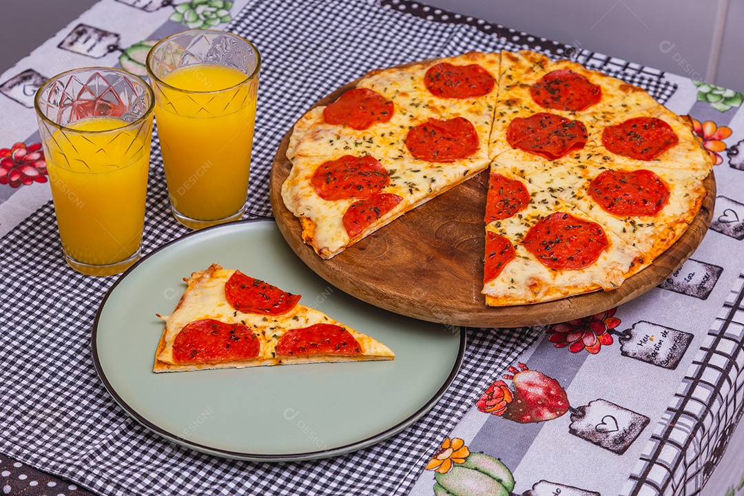 Deliciosa pizza de calabresa em fatias, pizza assada caseira. com suco de laranja
