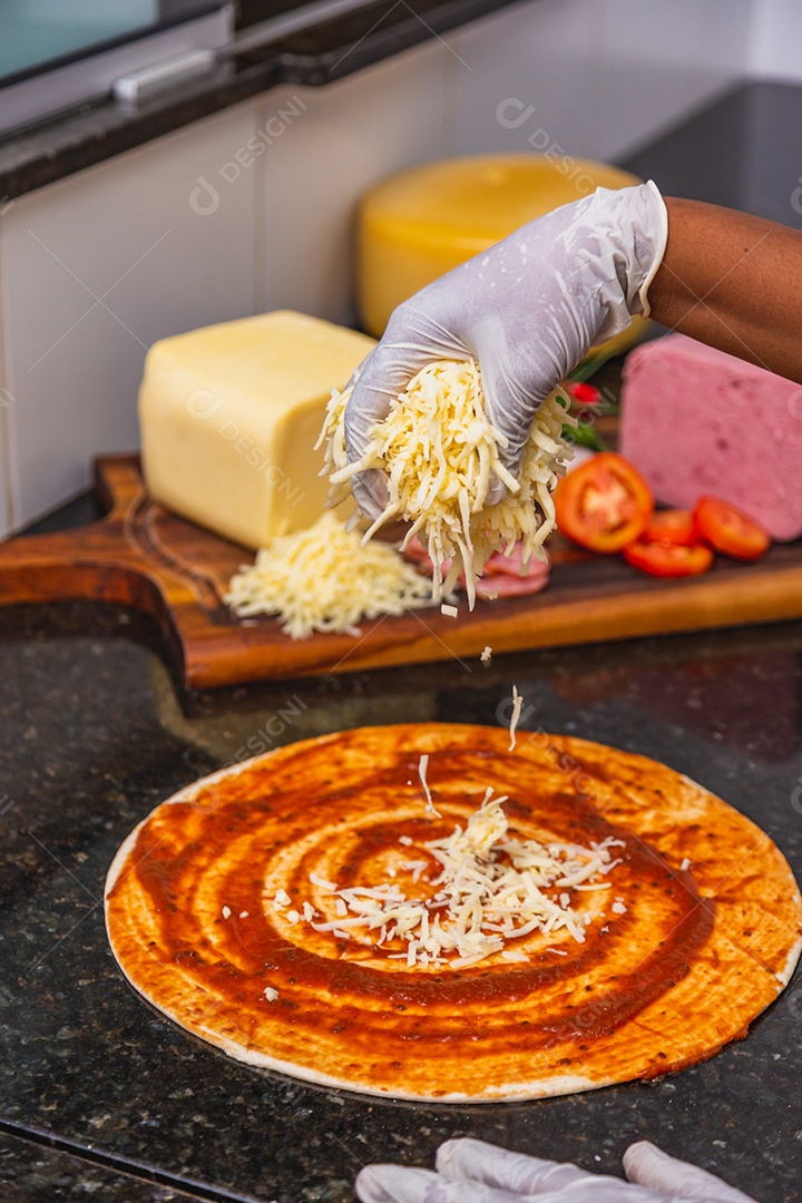 Preparação de pizza, espalhando queijo muçarela na massa de pizza