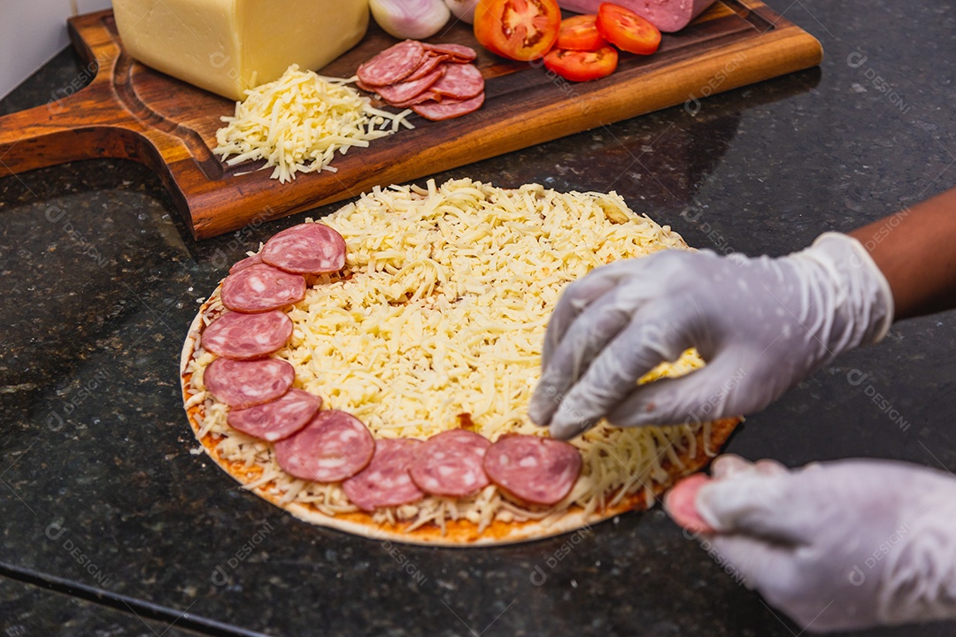 Preparação de pizza, espalhando rodelas de pepperoni e fatias na pizza