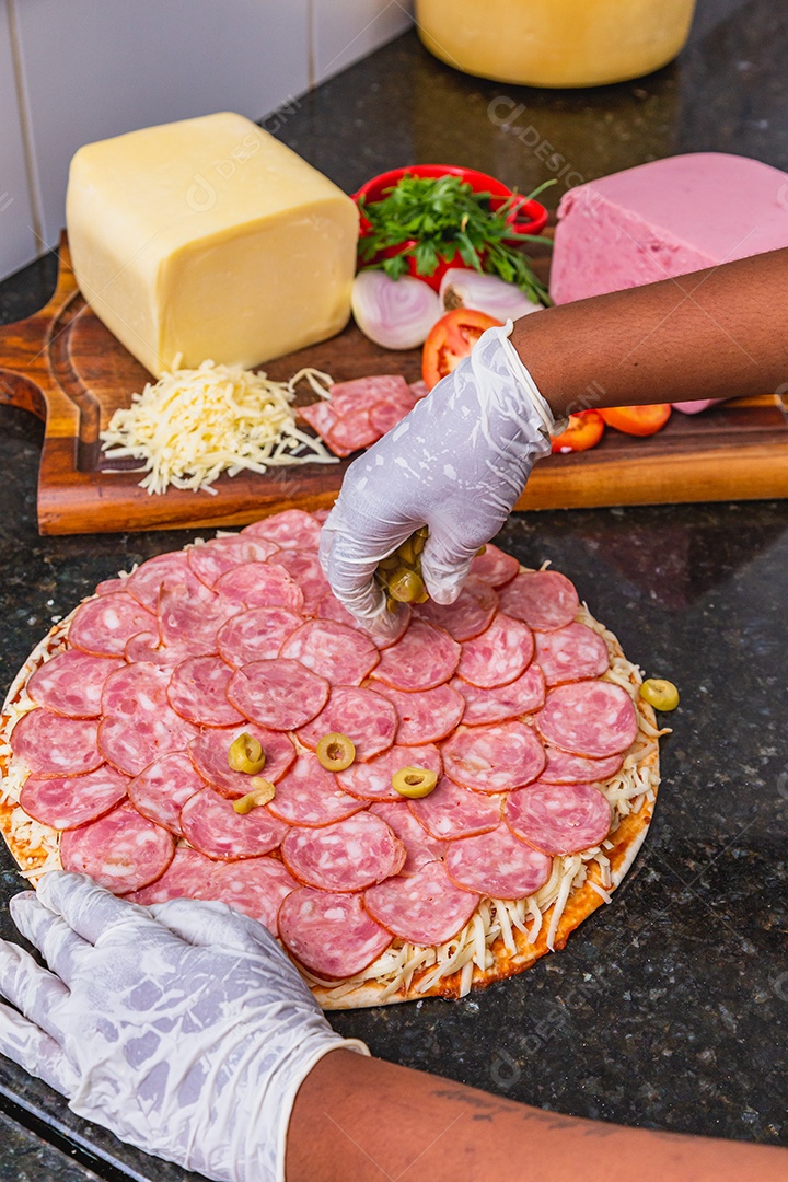 Preparação de pizza, espalhando rodelas de pepperoni e fatias na pizza