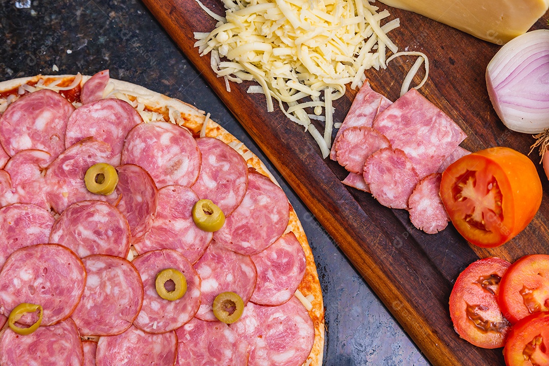 Preparação de pizza, espalhando rodelas de pepperoni e fatias na pizza