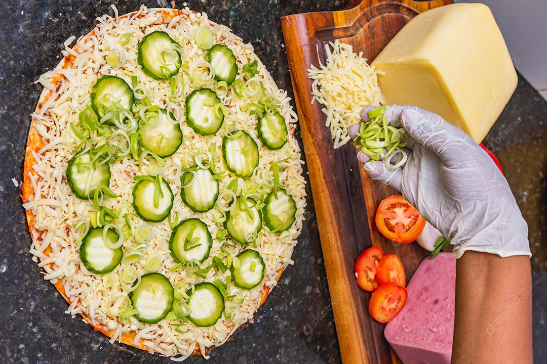 Preparação de pizza, espalhando fatias de pepino e fatias em vegetais