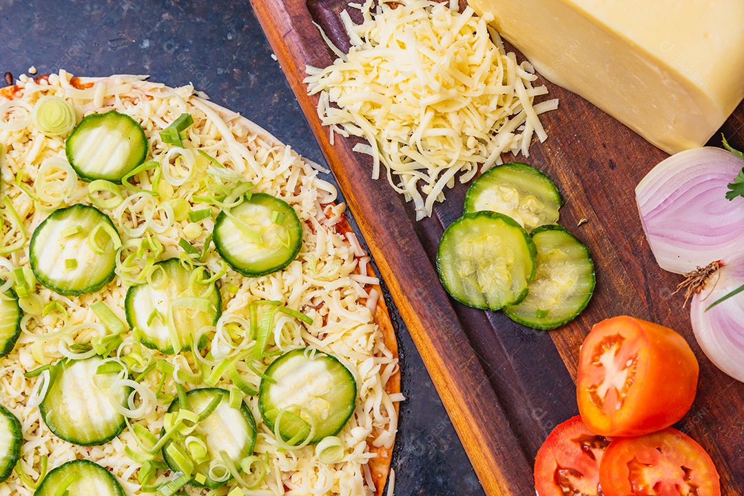 Preparação de pizza, espalhando fatias de pepino e fatias em vegetais