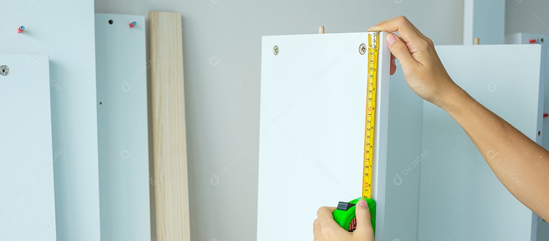 Mão de homem usando fita métrica para medir móveis em casa. faça você mesmo