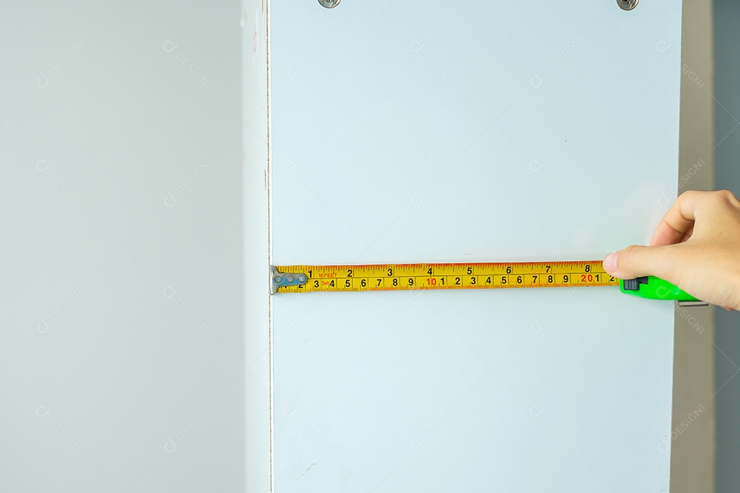 Mão de homem usando fita métrica para medir móveis em casa. faça você mesmo