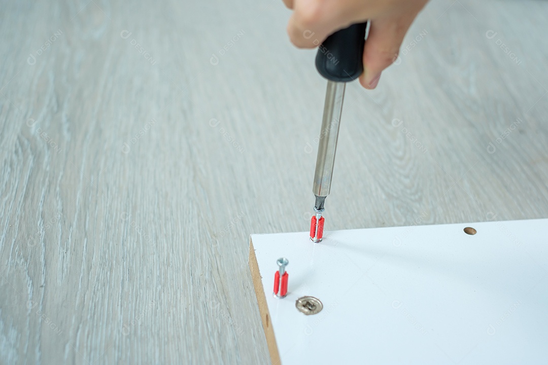 homem usando chave de fenda montando ou consertando móveis em casa.