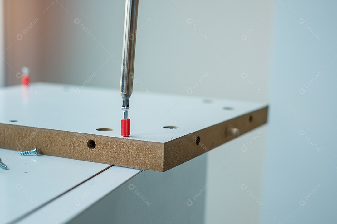 homem usando chave de fenda montando ou consertando móveis em casa.